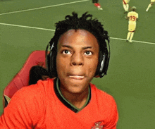 a man wearing headphones and a red nike shirt smiles on a tennis court