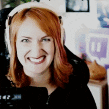 a woman with red hair wearing headphones is smiling