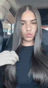 a woman is sitting in the back seat of a car holding her hair