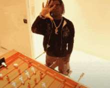 a man wearing a yves saint laurent necklace makes a peace sign