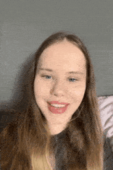 a young woman with long hair is smiling and looking at the camera