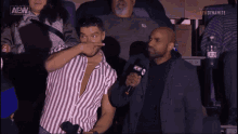 a man in a striped shirt is being interviewed by a man in a suit with a aew logo on the bottom