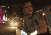 a woman is sitting in a car at night and looking out the window