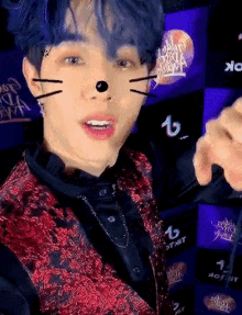 a young man with blue hair is wearing a cat mask and making a face .