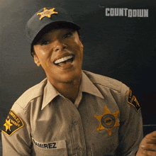 a woman in a sheriff 's uniform is laughing and wearing a hat