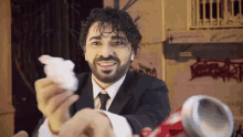 a man in a suit and tie is smiling and holding a piece of paper