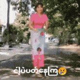a woman in a pink shirt and blue skirt is walking down a street ..