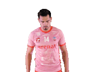 a man in a pink jersey with the number 14 on it stands with his arms crossed