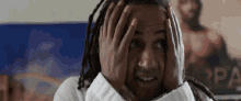 a man with dreadlocks is covering his face with his hands in front of a poster that says rpa