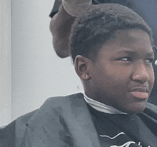 a young boy getting his hair cut by a barber