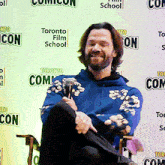 a man sitting in front of a toronto film school sign