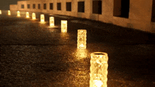 a row of candles are lit up on a wet sidewalk