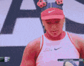 a woman wearing a red hat and a white tank top with the word nike on it
