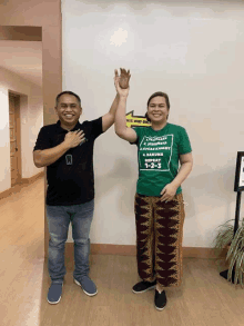 a man and a woman giving each other a high five in front of a sign that says " it 's way only "