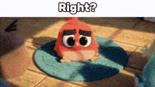 a red angry bird is sitting on a blue rug on a wooden table .