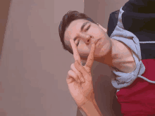 a young man is making a peace sign with his fingers
