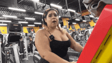 a woman in a black tank top is using an exercise machine in a gym
