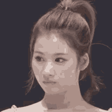 a close up of a woman 's face with a ponytail and a ponytail .