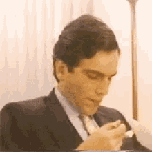 a man in a suit and tie is sitting at a table eating a piece of bread .