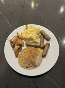 a white plate with eggs pancakes sausages and potatoes on it