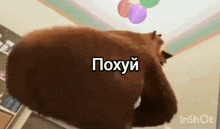 a bear is standing in a room with balloons hanging from the ceiling and a caption in russian .