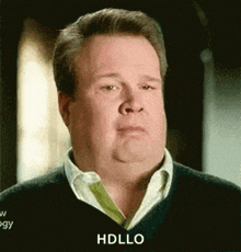 a man with a sweater on is making a funny face and saying hello