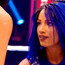 a woman with blue hair is standing next to a man in a ring .