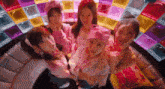 a group of girls are standing next to each other on a couch in front of a colorful background .