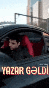 a man is sitting in a black car with red seats