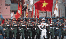 a group of soldiers marching in a parade with a flag that has a yellow star on it