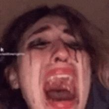a close up of a woman 's face with blood coming out of her eyes and mouth .