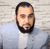 a man with a beard and mustache is wearing a light blue suit .