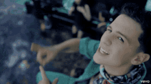 a boy in a green shirt is giving a thumbs up