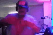 a man wearing headphones and a hat is dancing in front of a microphone in a dark room .