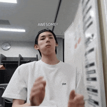 a man wearing a white t-shirt that says cgp stands in front of a white board