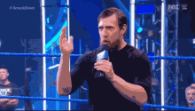 a man speaking into a microphone in a wrestling ring with the words #smackdown on the bottom