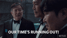 a man in a tuxedo says " our time 's running out " in front of two other men