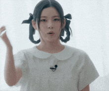 a woman wearing a white shirt has a microphone on her neck