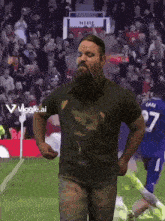 a man with a beard wearing a viggle.ai shirt stands on a field