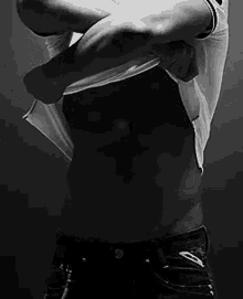 a black and white photo of a man taking off his shirt and jeans .