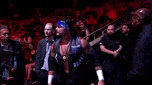 a man in a tna wrestling shirt stands in the middle of a crowd