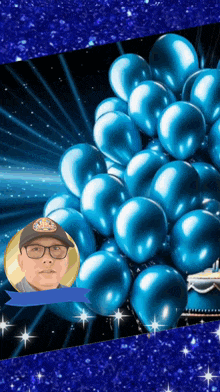 a man wearing glasses is surrounded by blue balloons and a blue ribbon