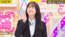 a woman in a suit and white shirt is making a funny face on a pink background .