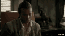 a man in a suit and white shirt is sitting in a chair and looking at the camera .