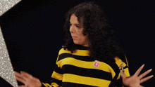 a woman wearing a yellow and black striped sweater with a pink pin that says ' strawberry ' on it