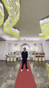 a man is standing on a red carpet in front of a wedding stage