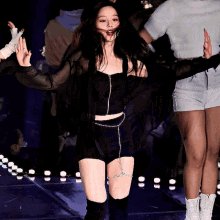a woman in a black top and white shorts is dancing on a stage