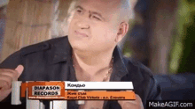 a bald man is sitting in front of a sign that says diapason records on make a gif .