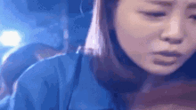 a close up of a woman 's face in a blue shirt with a sad look on her face .