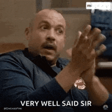a man is clapping his hands in a very well said sir gif .